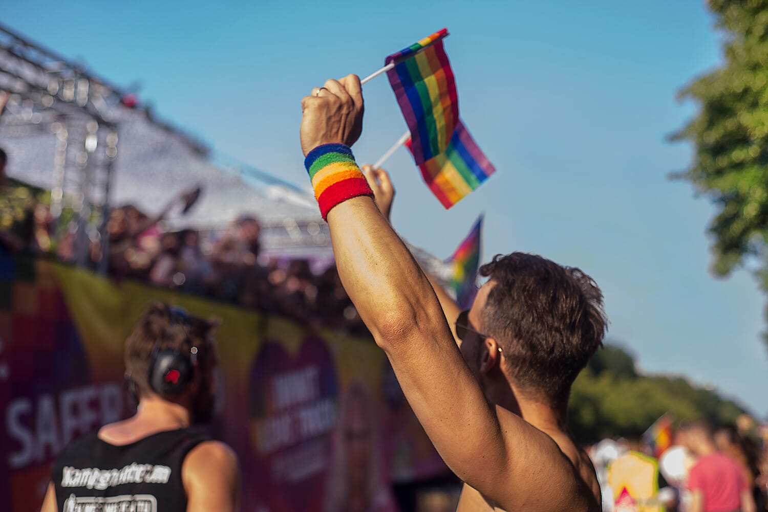 People at CSD Dresden: A person holds up a rainbow flag.