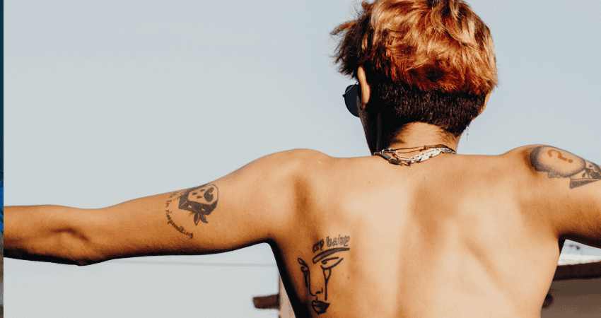 Oberkörper einer Person mit Tattoos und offenen Armen – Symbolbild für Freiheit, Sexualität und unterschiedliche Schutzstrategien.